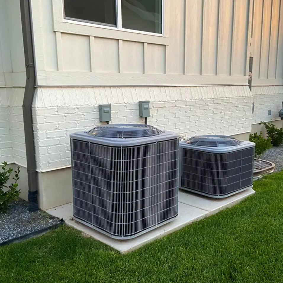 Dos condensadores de HVAC nuevos junto a una casa