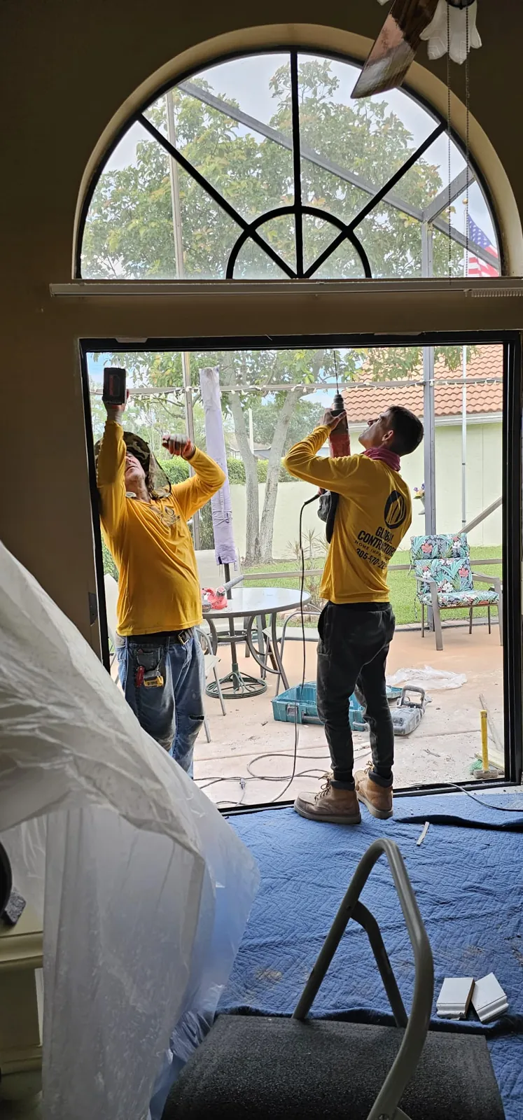 Instaladores de Global Contractors colocando vidrio de impacto bajo una ventana en arco