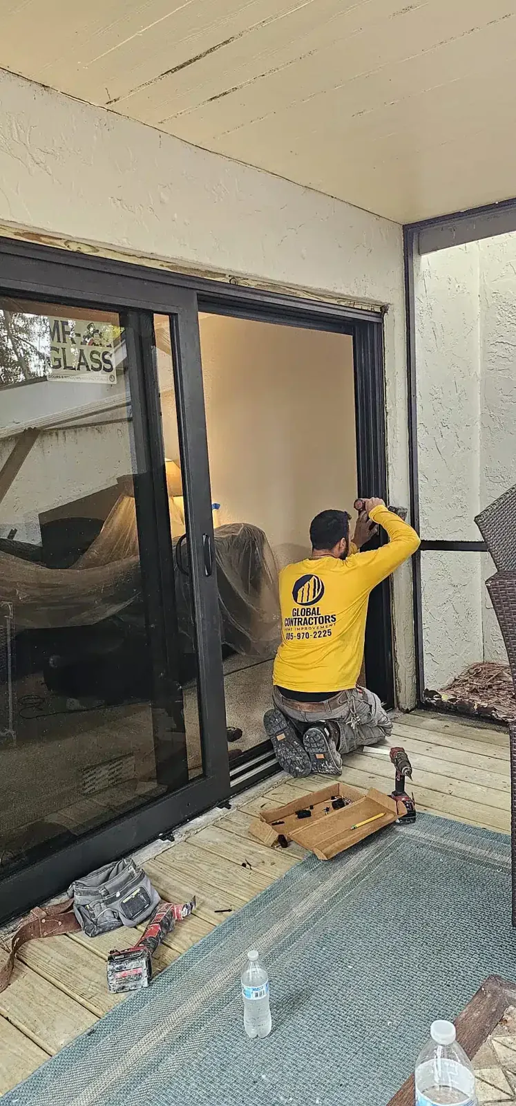 Instalador de Global Contractors colocando una puerta corrediza de vidrio de impacto