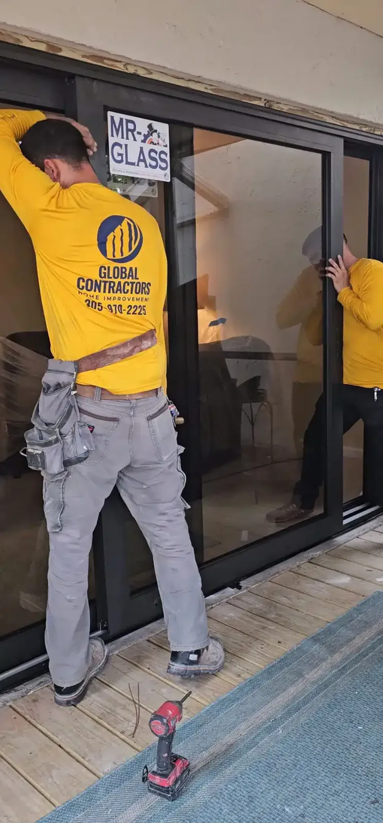 Instalador de Global Contractors colocando una puerta corrediza de vidrio de impacto