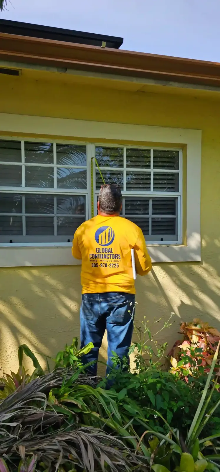 Un instalador de Global Contractors midiendo una ventana