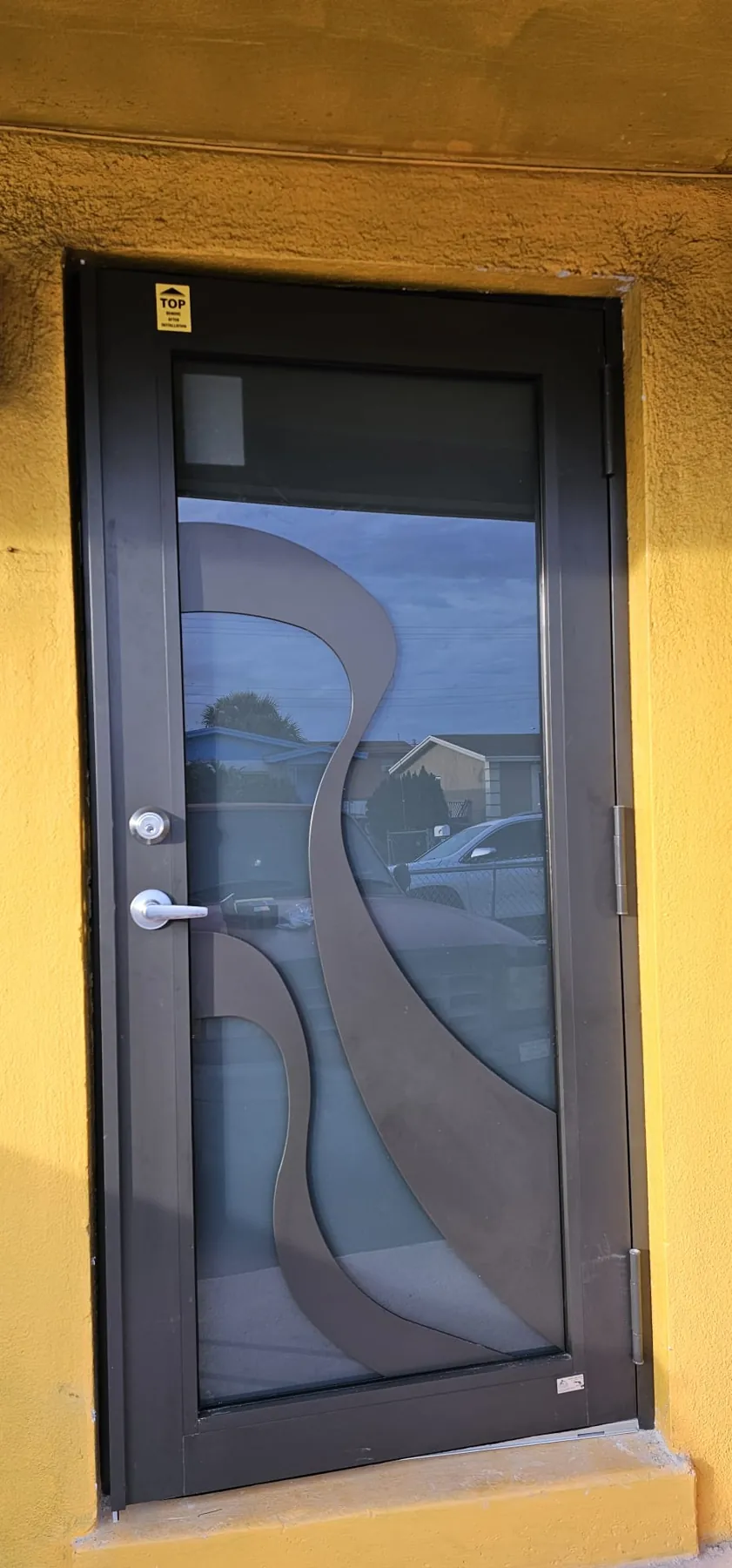 Puerta de entrada de impacto color bronce con vidrio decorativo