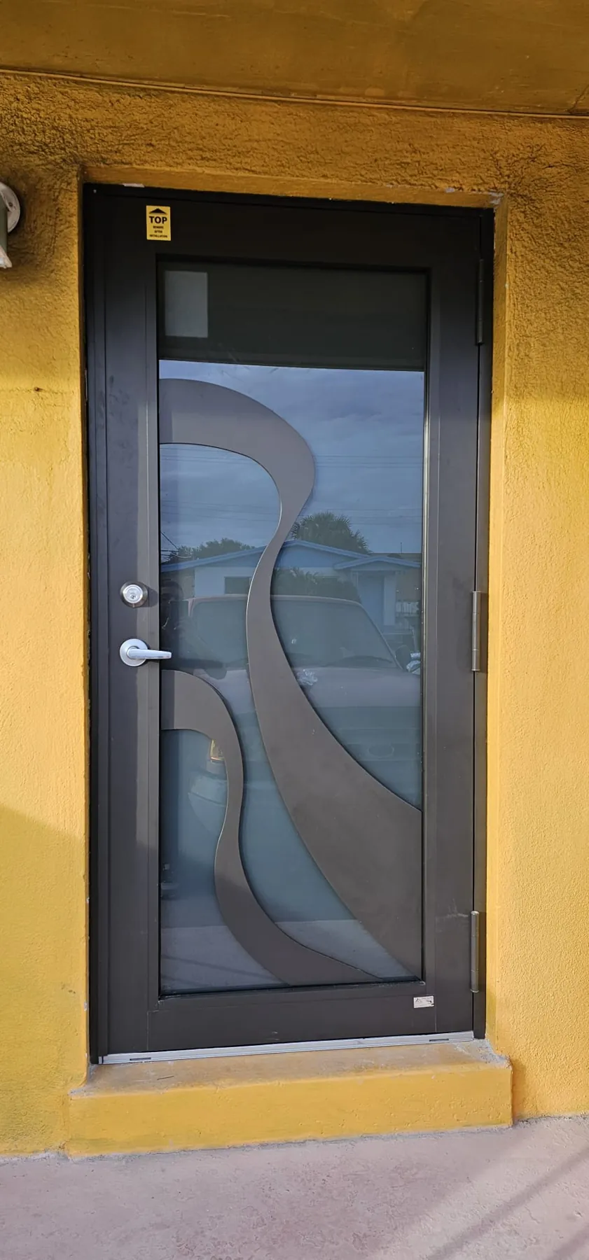 Puerta de entrada de impacto color bronce con vidrio decorativo, vista desde afuera