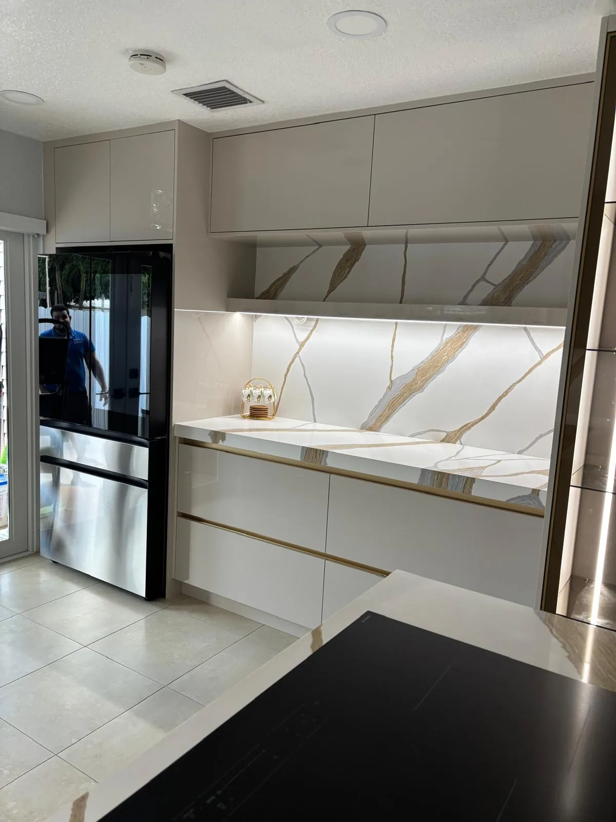 Finished kitchen with white cabinetry, a quartz backsplash and a stainless refrigerator