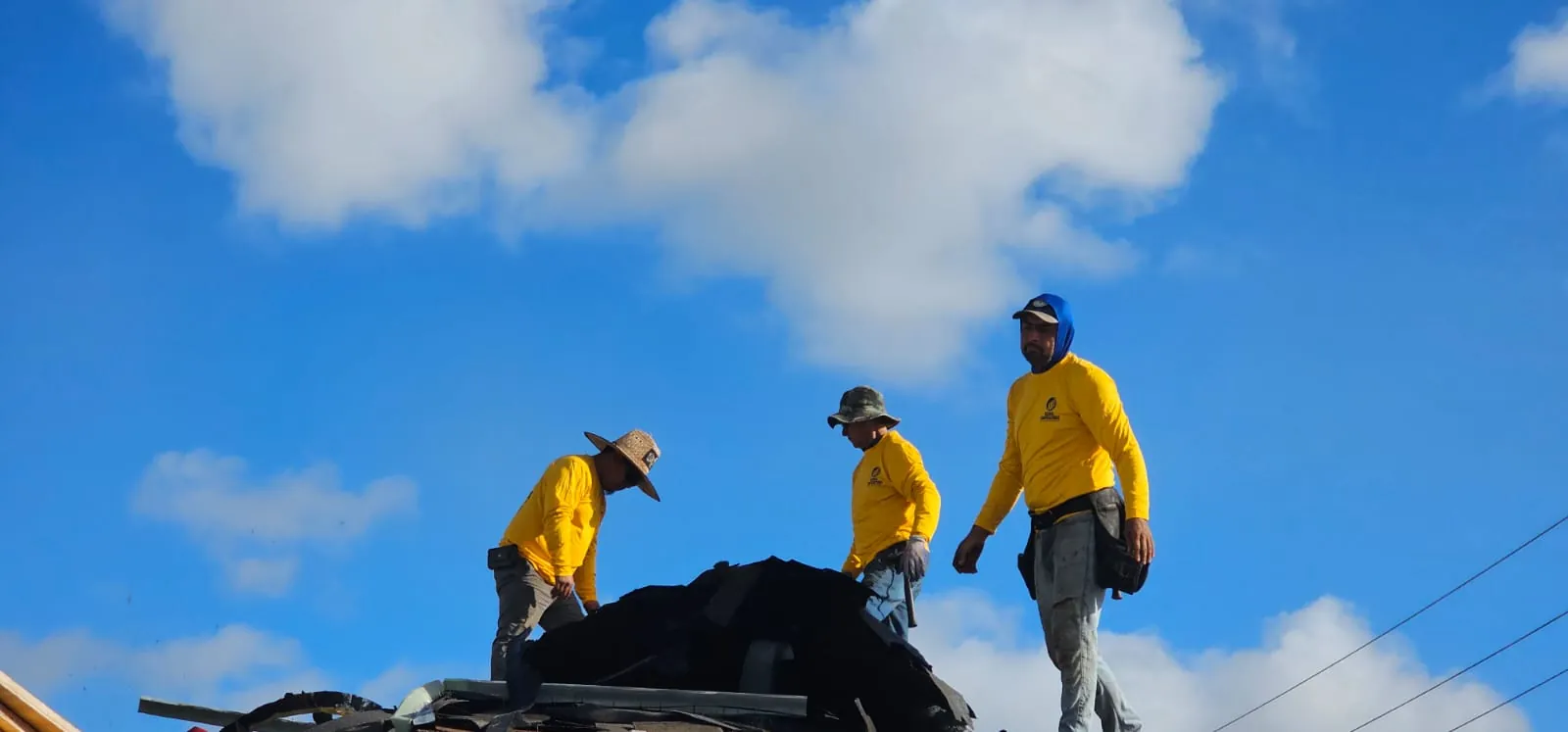 Cuadrilla de Global Contractors quitando el techo viejo, con una escalera en el borde
