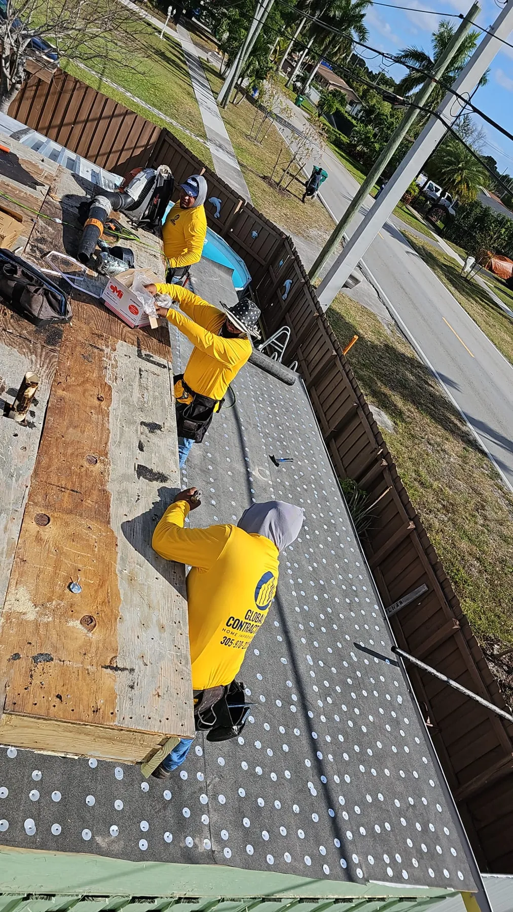 Cuadrilla de Global Contractors trabajando a lo largo del borde de un techo