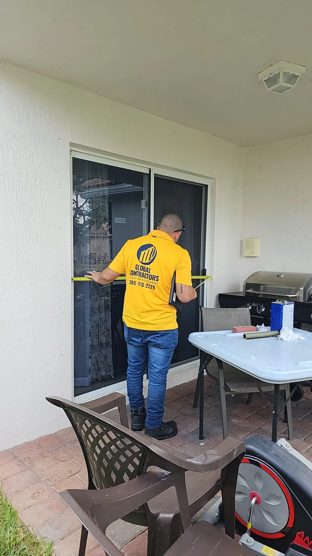 Instalador de Global Contractors midiendo una puerta corrediza de vidrio