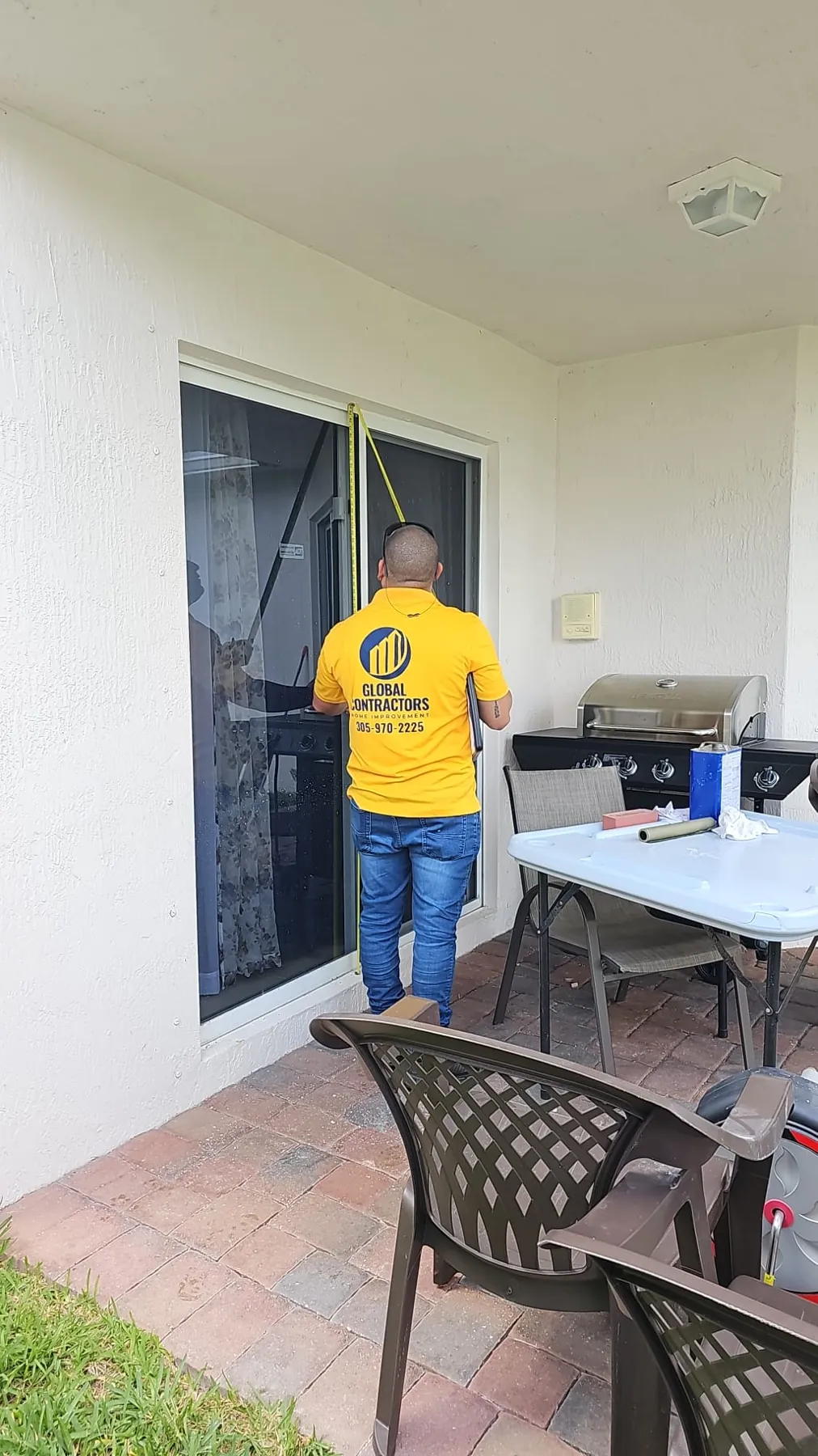 Instalador de Global Contractors midiendo una puerta corrediza de vidrio