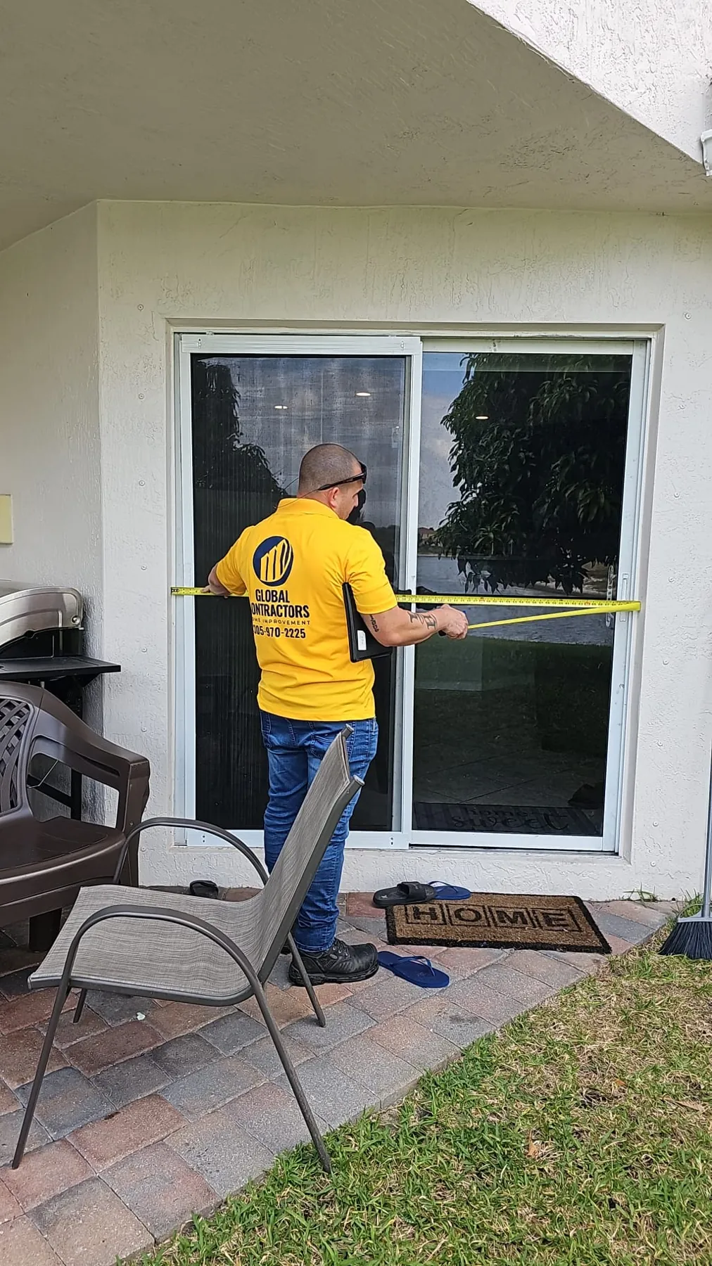 Instalador de Global Contractors midiendo una puerta corrediza de vidrio