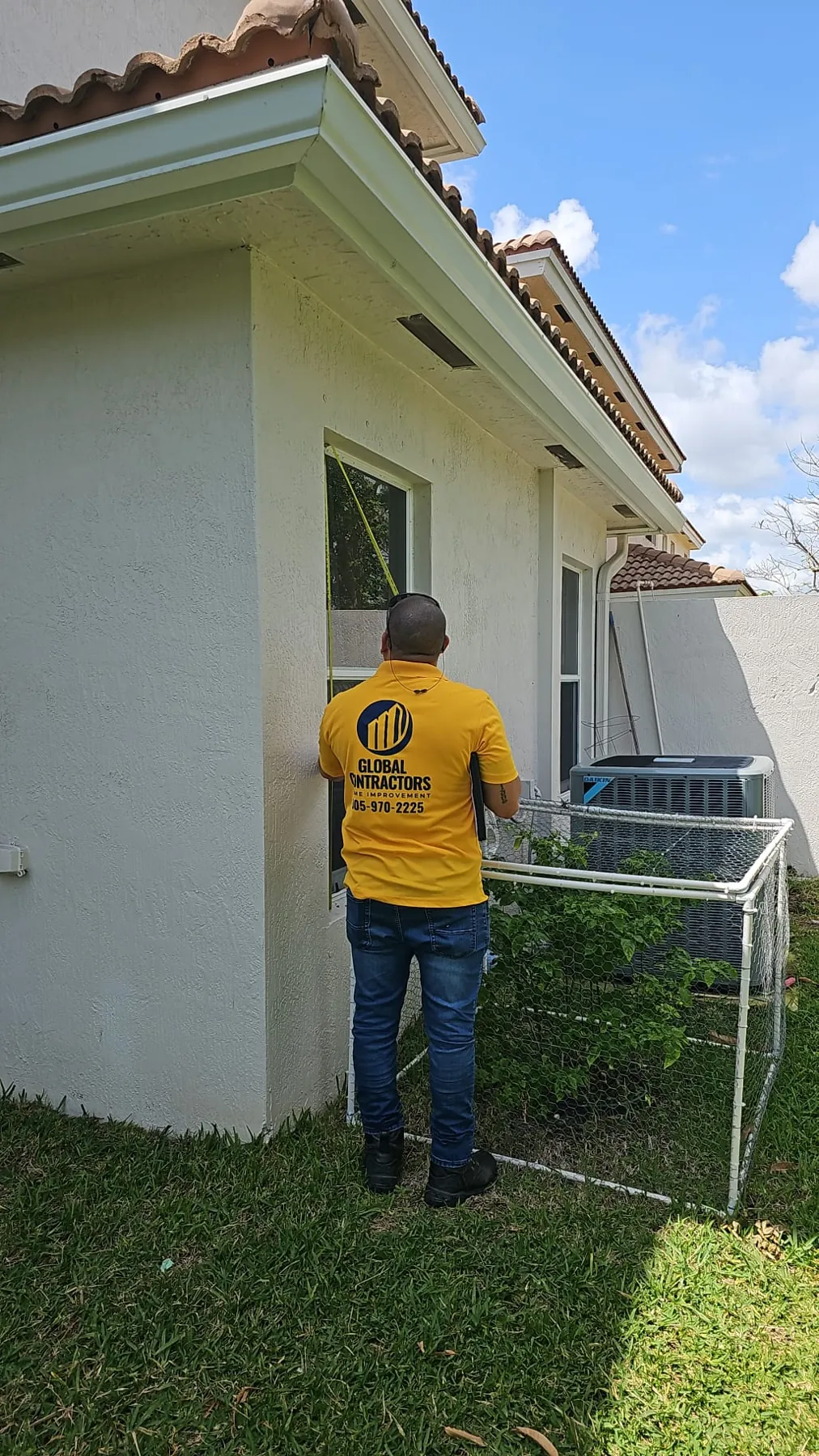 Instalador de Global Contractors midiendo una ventana desde afuera