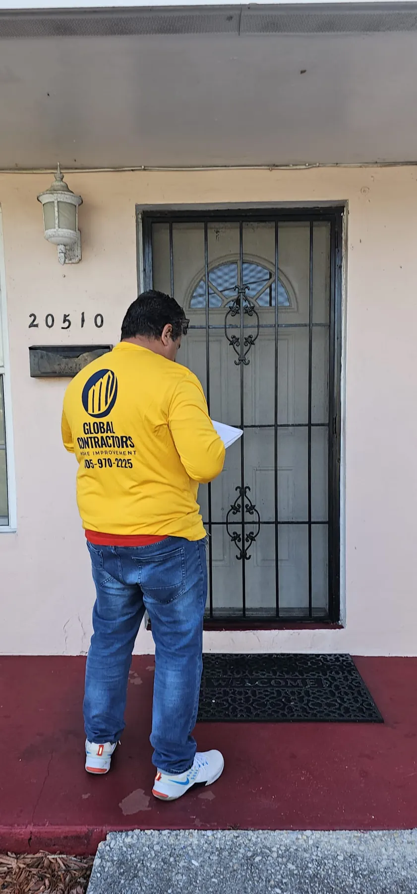 Instalador de Global Contractors midiendo una puerta de entrada con reja de seguridad