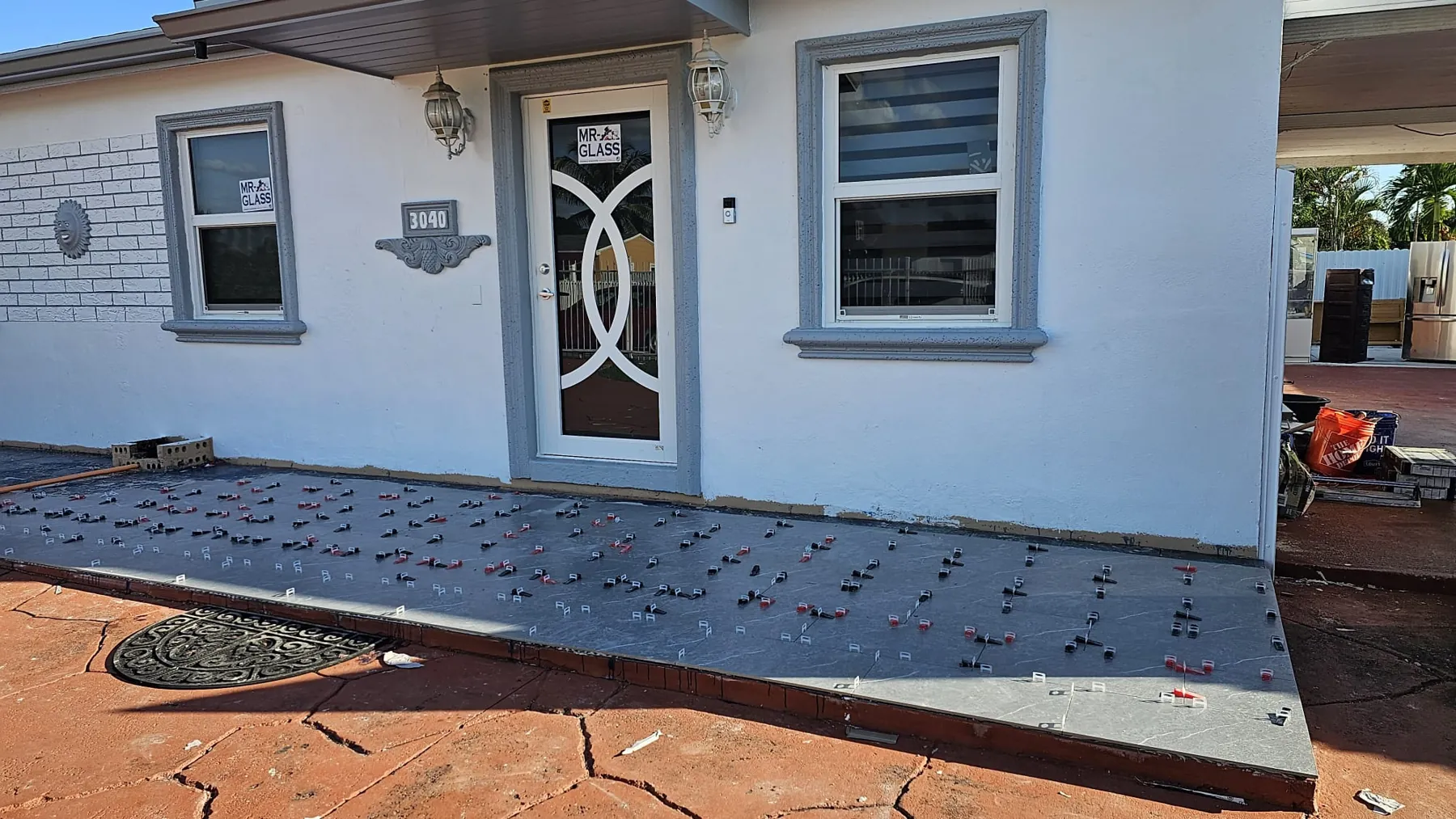 Frente de una casa con ventanas de impacto nuevas y una puerta de impacto decorativa